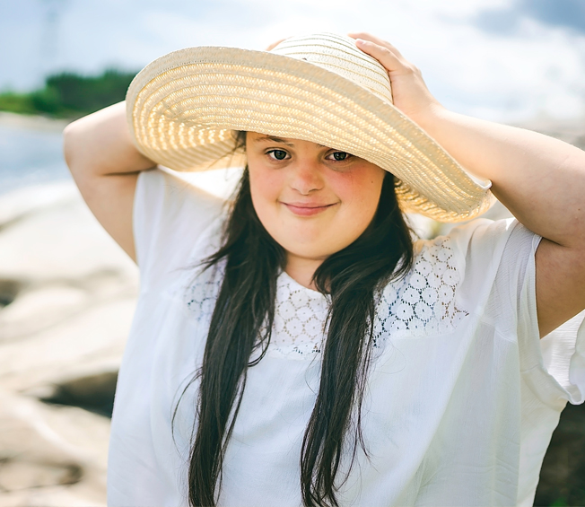 woman wearing a hat and smiling at the beach